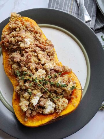 half of a butternut squash stuffed with cooked sausage, goat cheese, and quinoa.