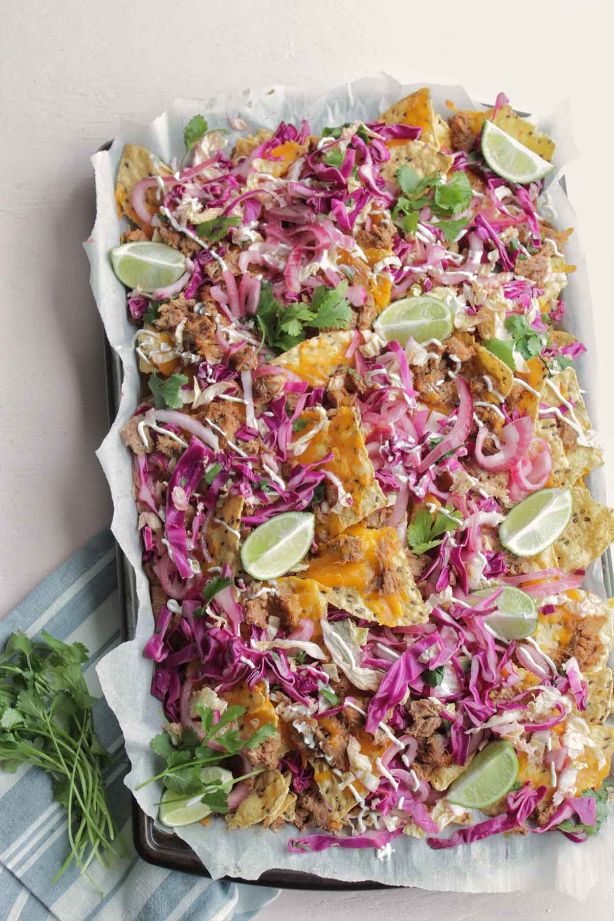 pulled pork nachos topped with slaw on a sheet pan.