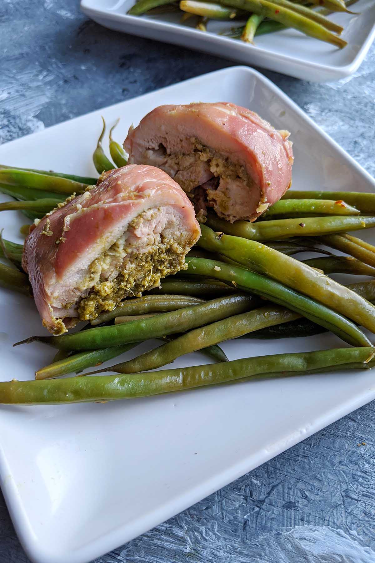 prosciutto covered chicken on top of green beans.