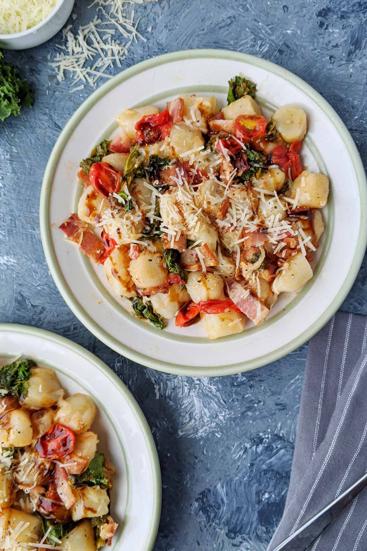 small plate of gnocchi with bacon and vegetables.