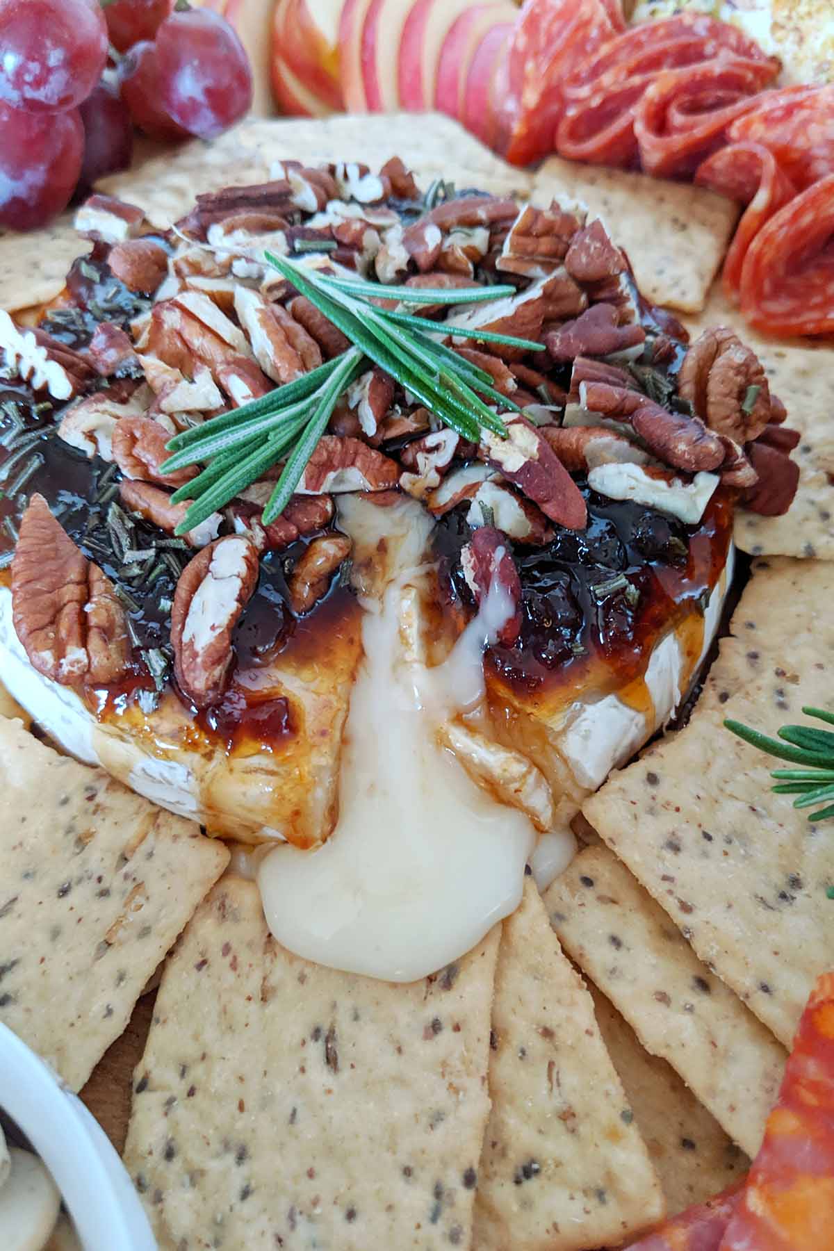 baked brie cheese topped with nuts on a charcuterie board.