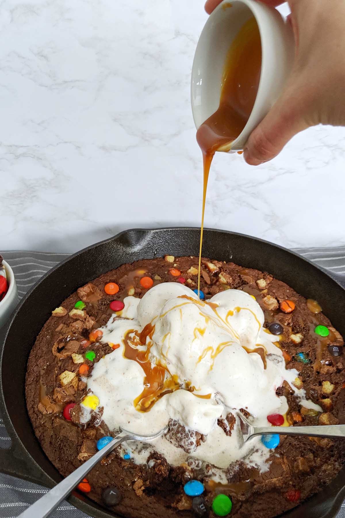 skillet brownie with pouring caramel