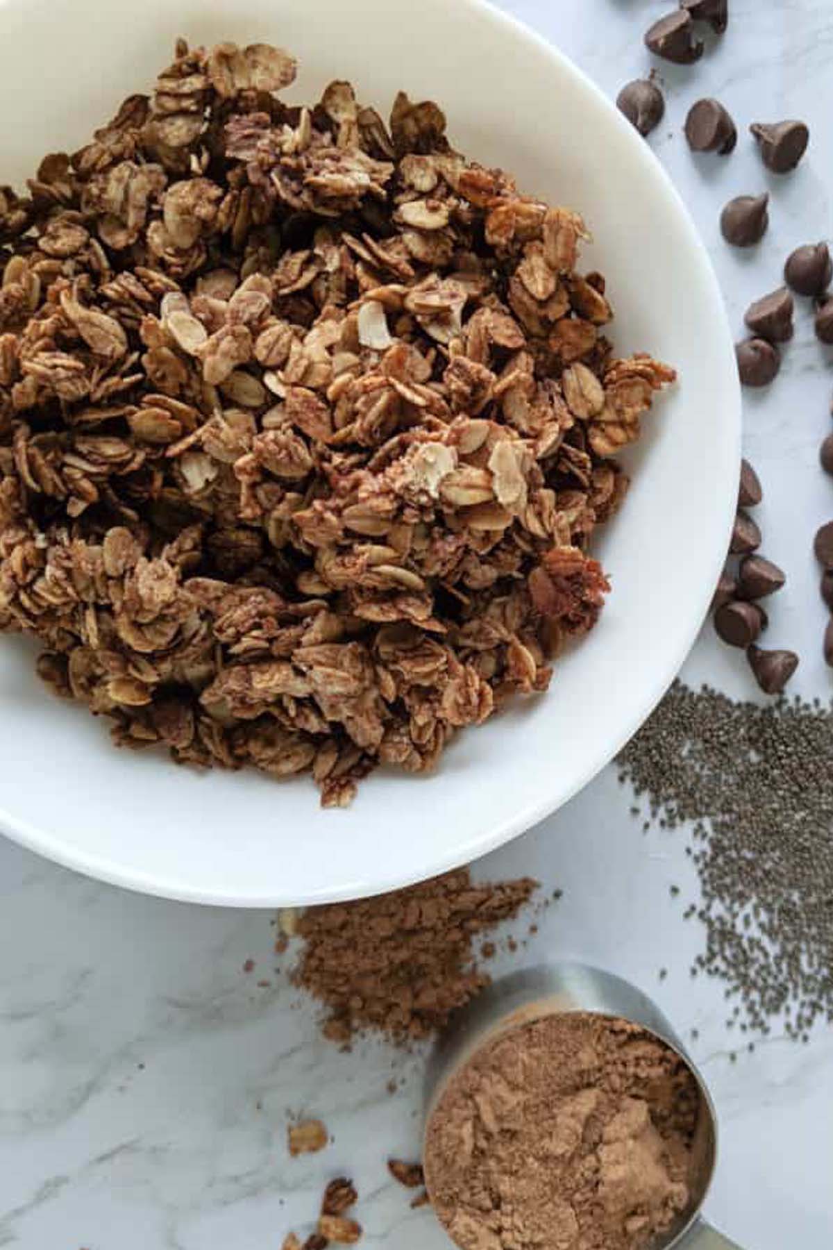 chocolate granola next to measuring cup with cocoa powder.