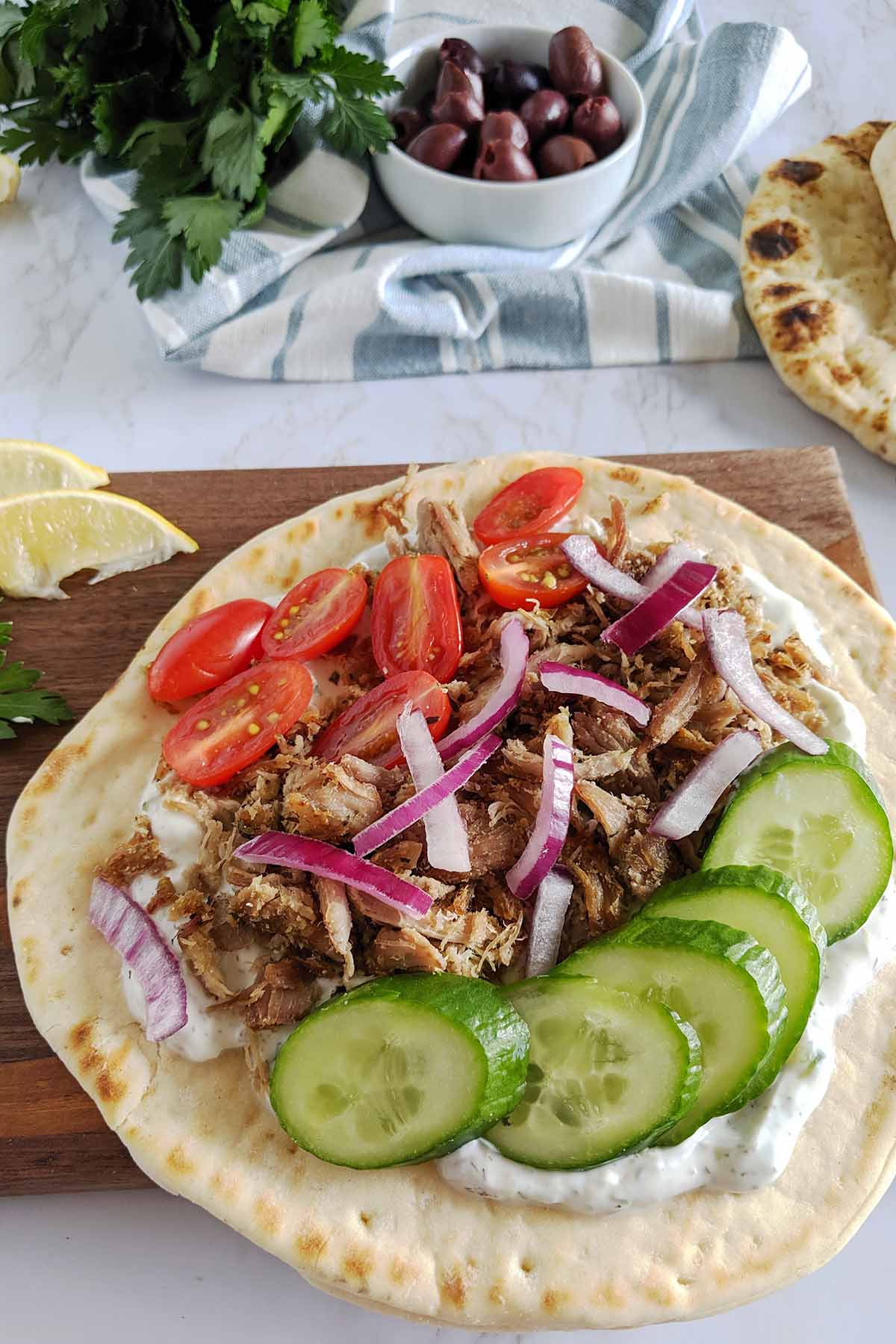 greek style gyro on pita bread with cucumbers, tomatoes, and onion.