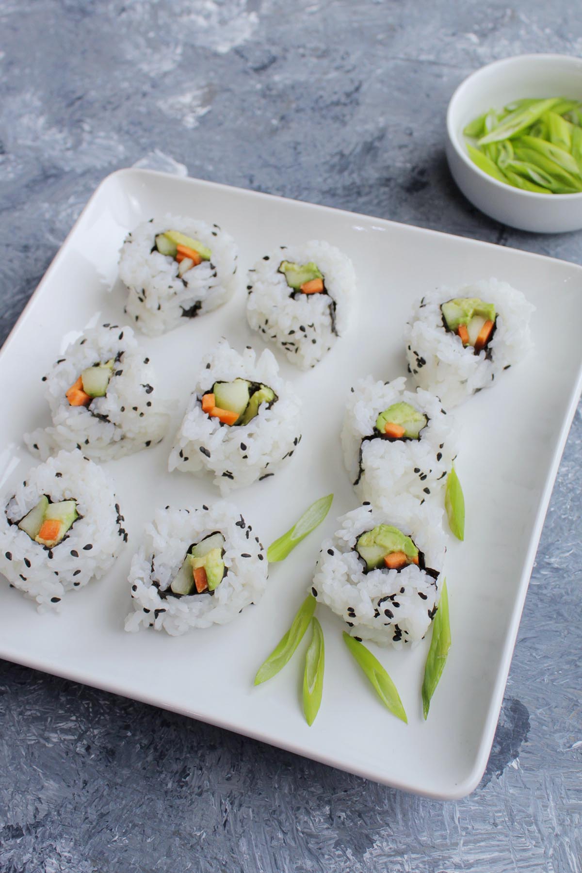 vegetable sushi roll garnished with green onions.