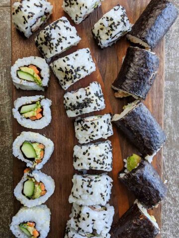 homemade sushi rolls on wooden cutting board.