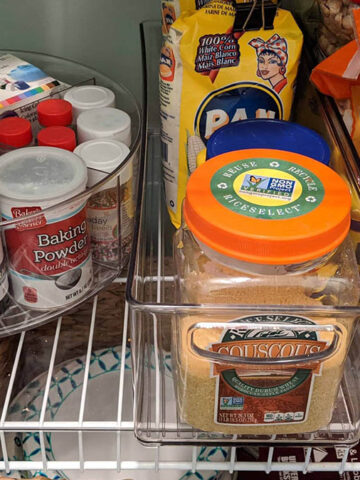 pantry shelves filled with various food items in clear organization bins.