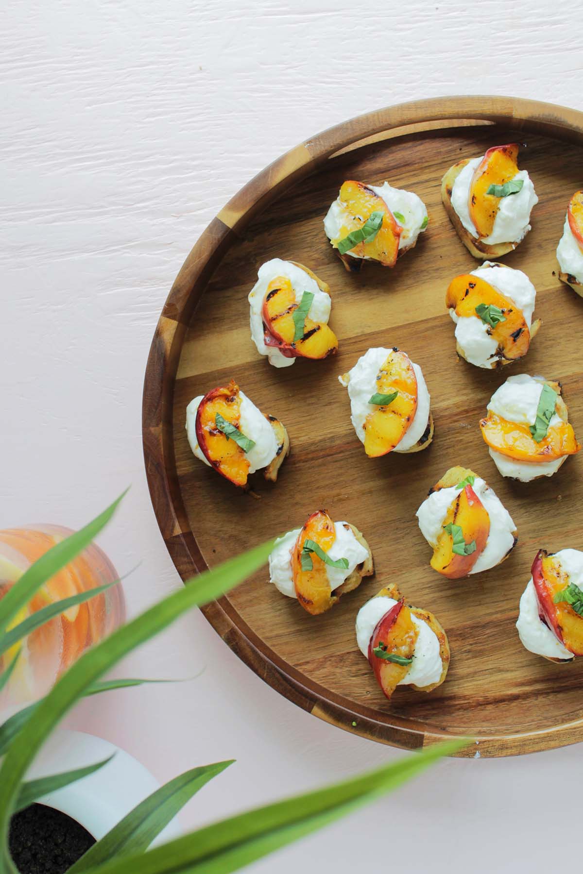 peach crostini with ricotta on wooden serving tray.