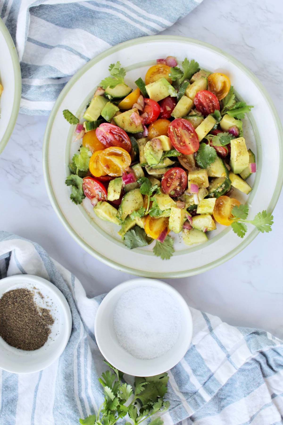 avocado, tomato, and cucumber salad on a green rimmed serving plate.