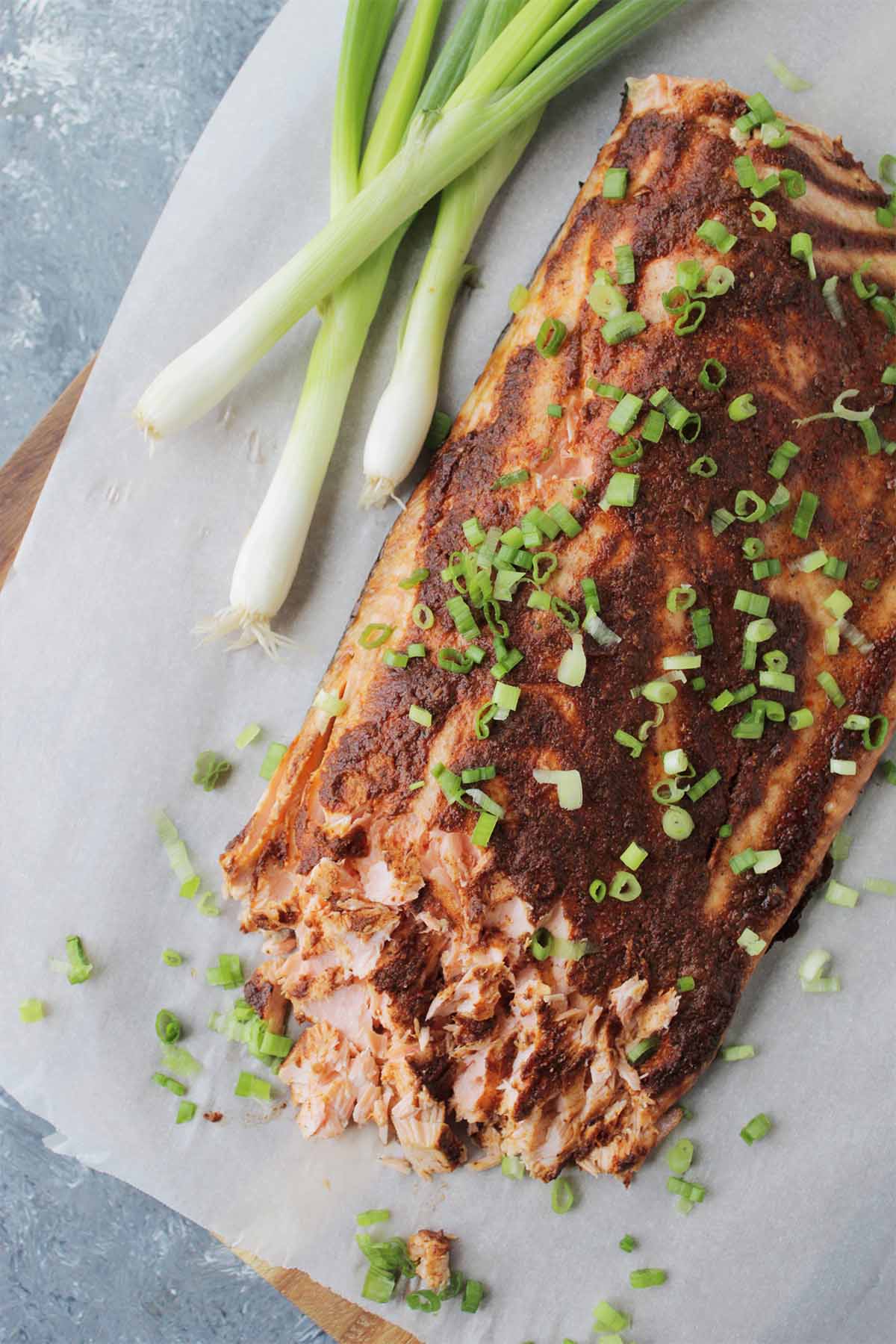 adobo seasoning on salmon fillet garnished with green onions.