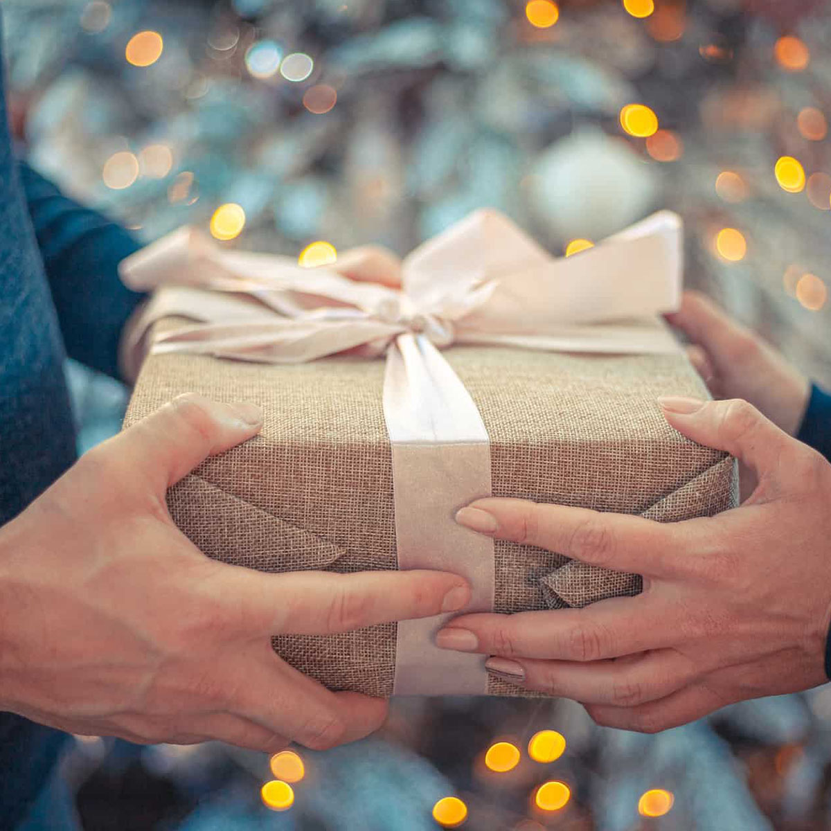 two hands holding a wrapped gift box.