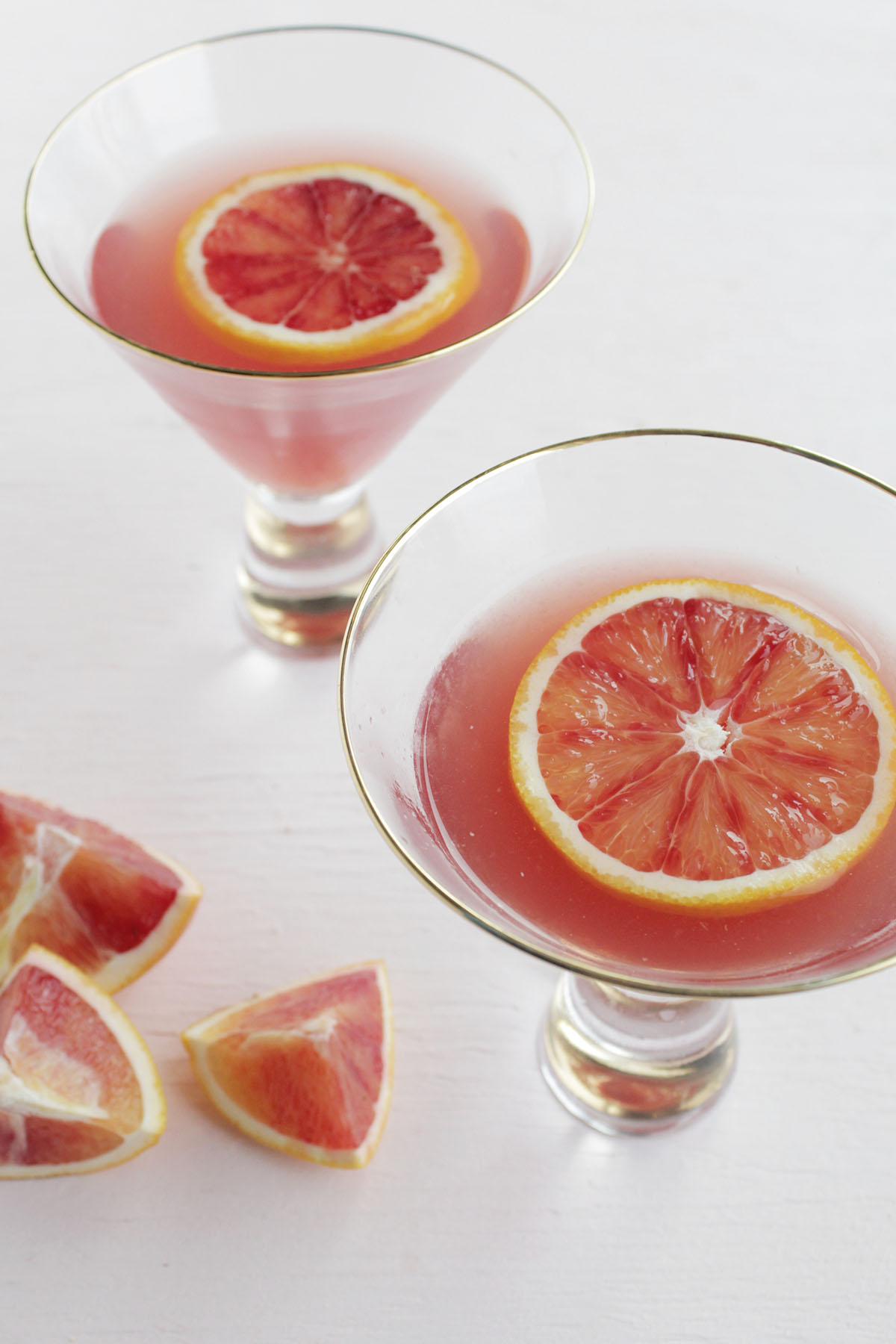 two martini glasses filled with pomegranate and blood orange martinis.