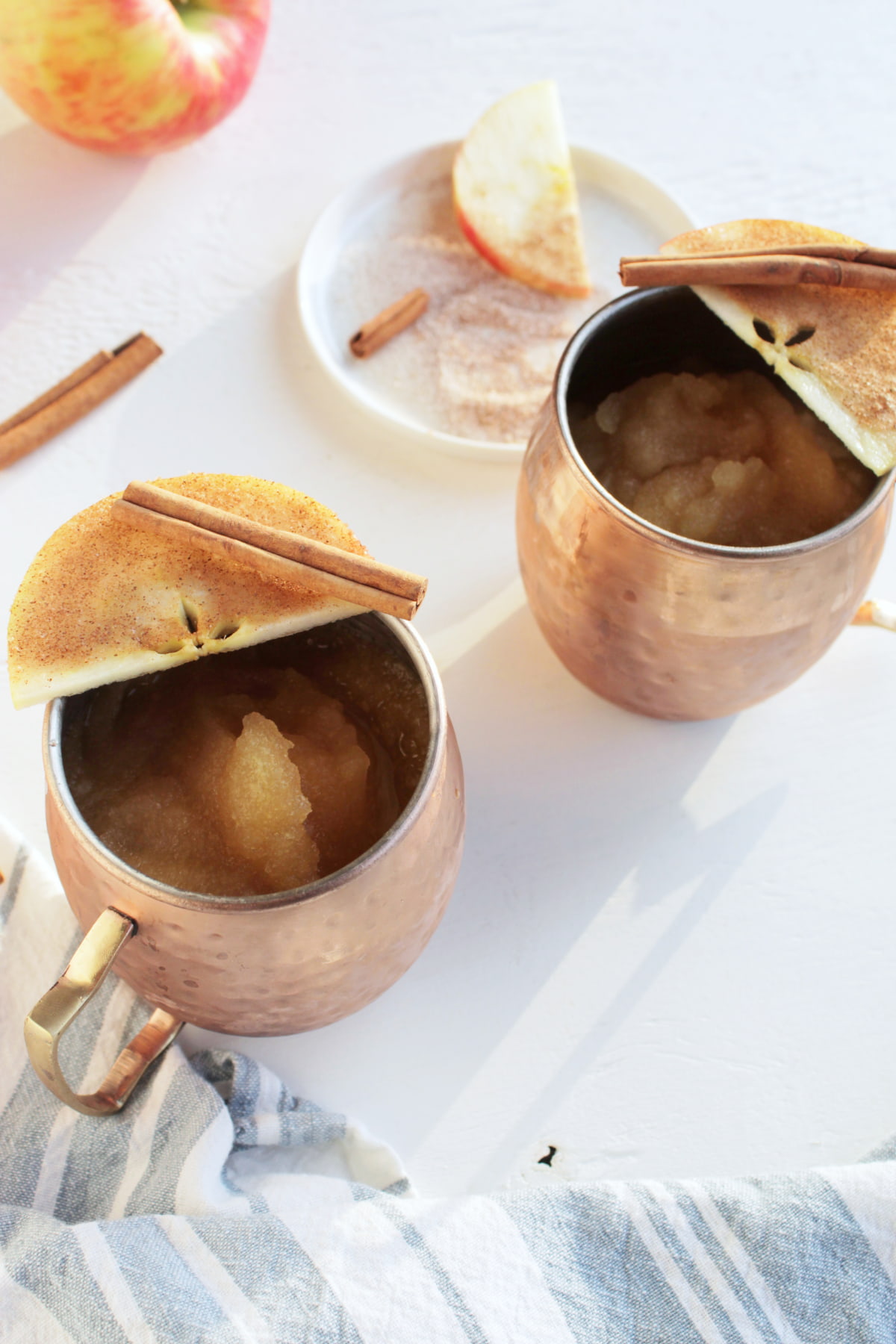 alcoholic slushie in copper mug with apple slice on top.