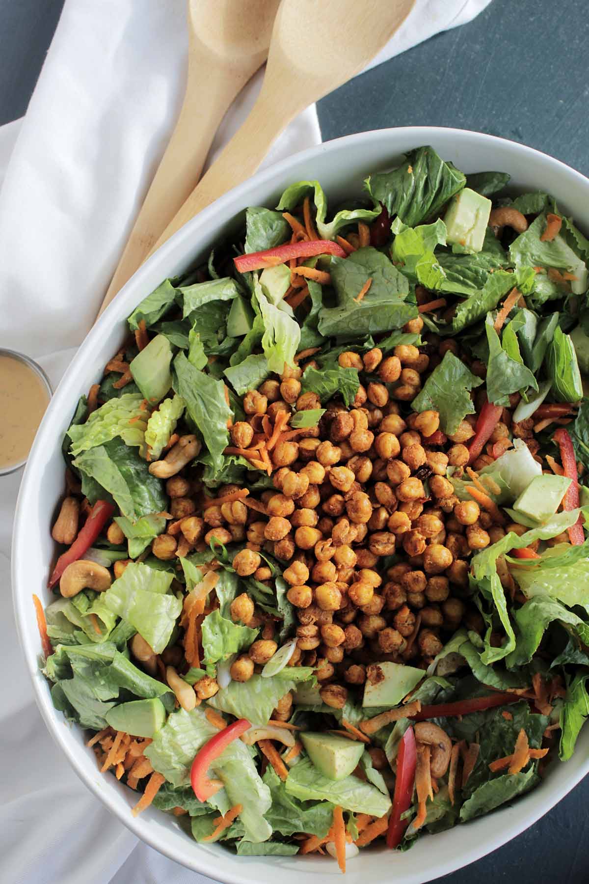 green salad in a white serving bowl topped with chickpeas.