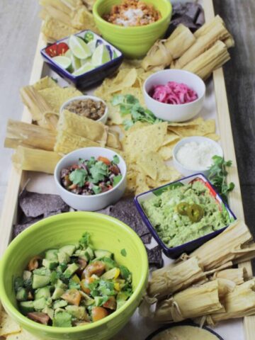 long tamale platter with various dips in colorful bowls.