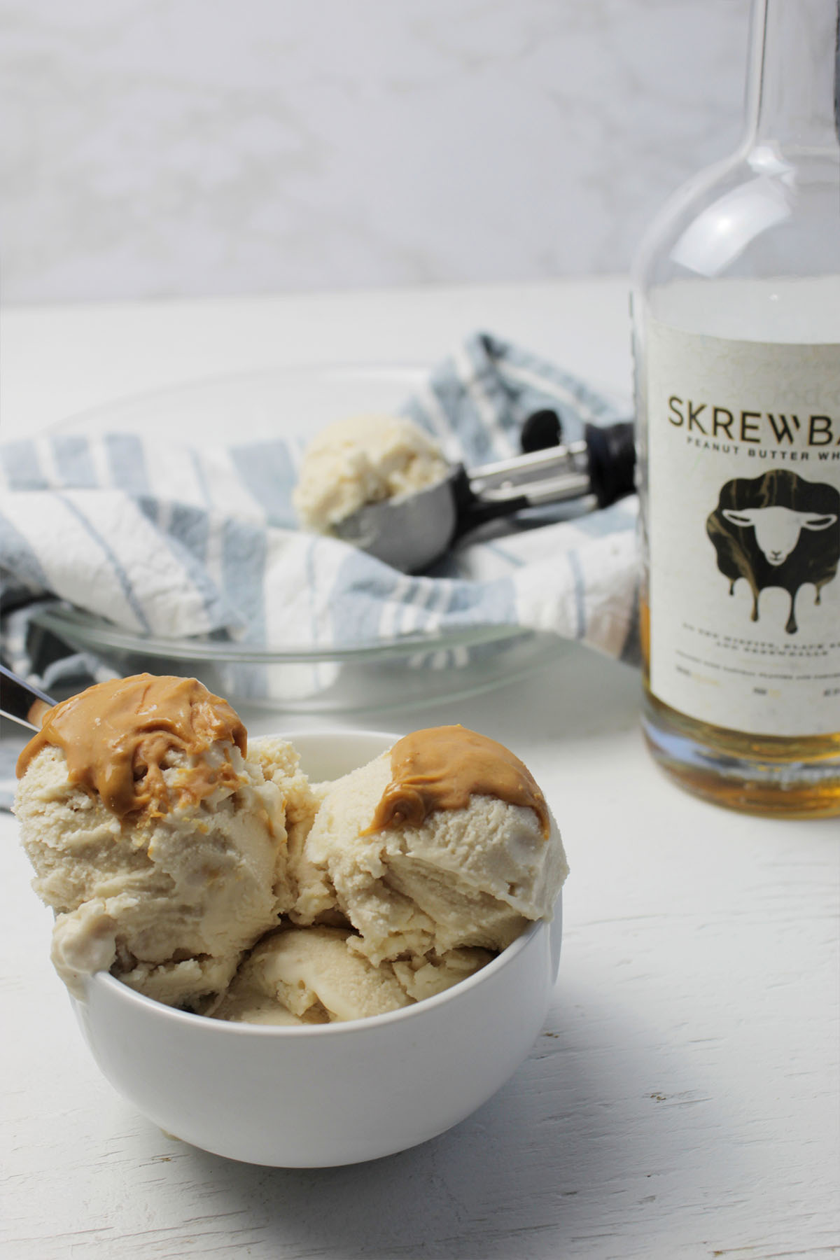 ice cream scoops in a serving bowl next to alcohol bottle.