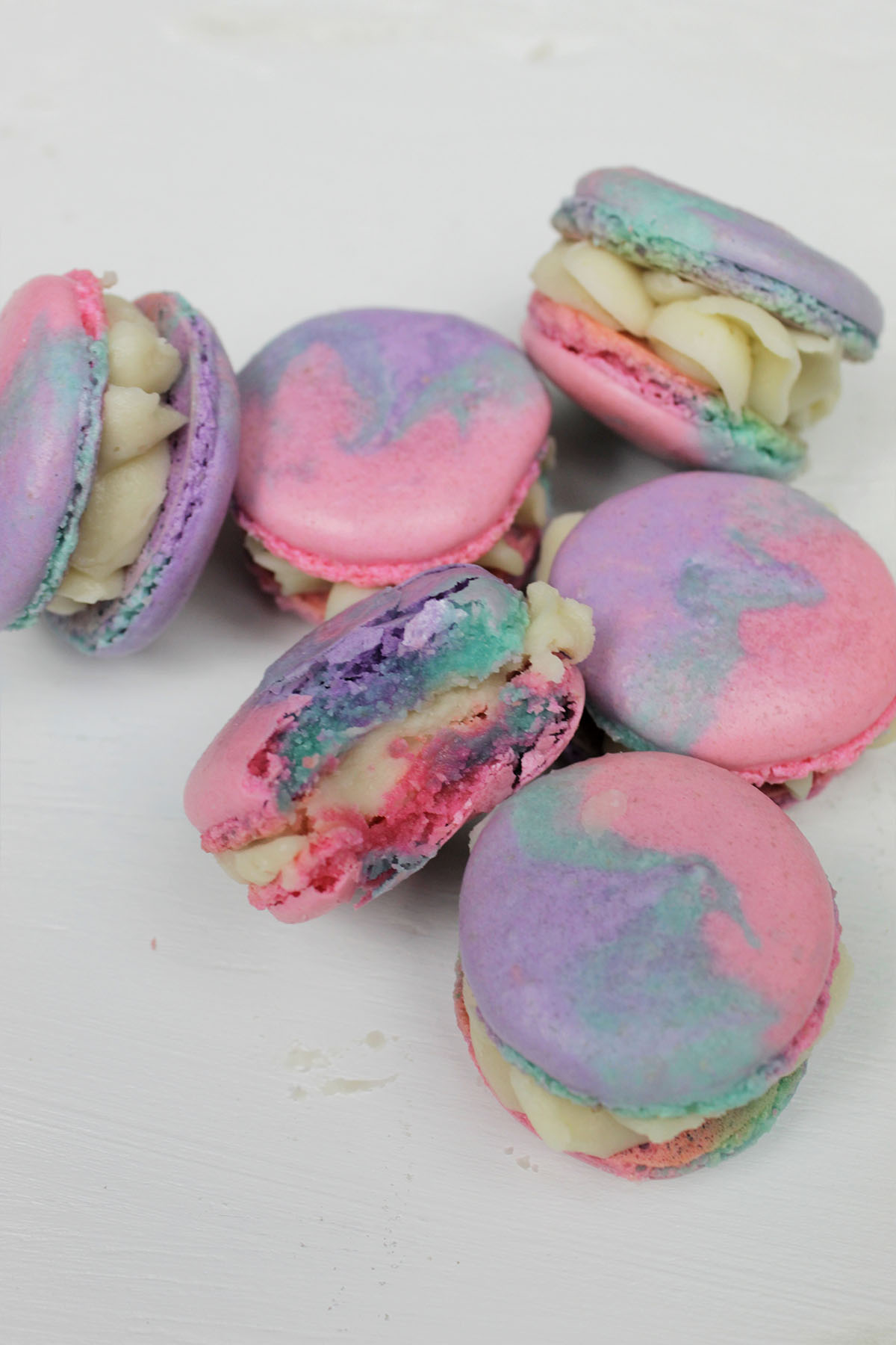 Pile of tie-dye macarons, with one cut in half.