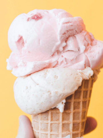 hand holding strawberry ice cream cone.