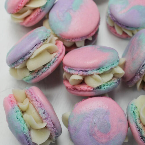 buttercream filled tie dye macarons laying next to each other.