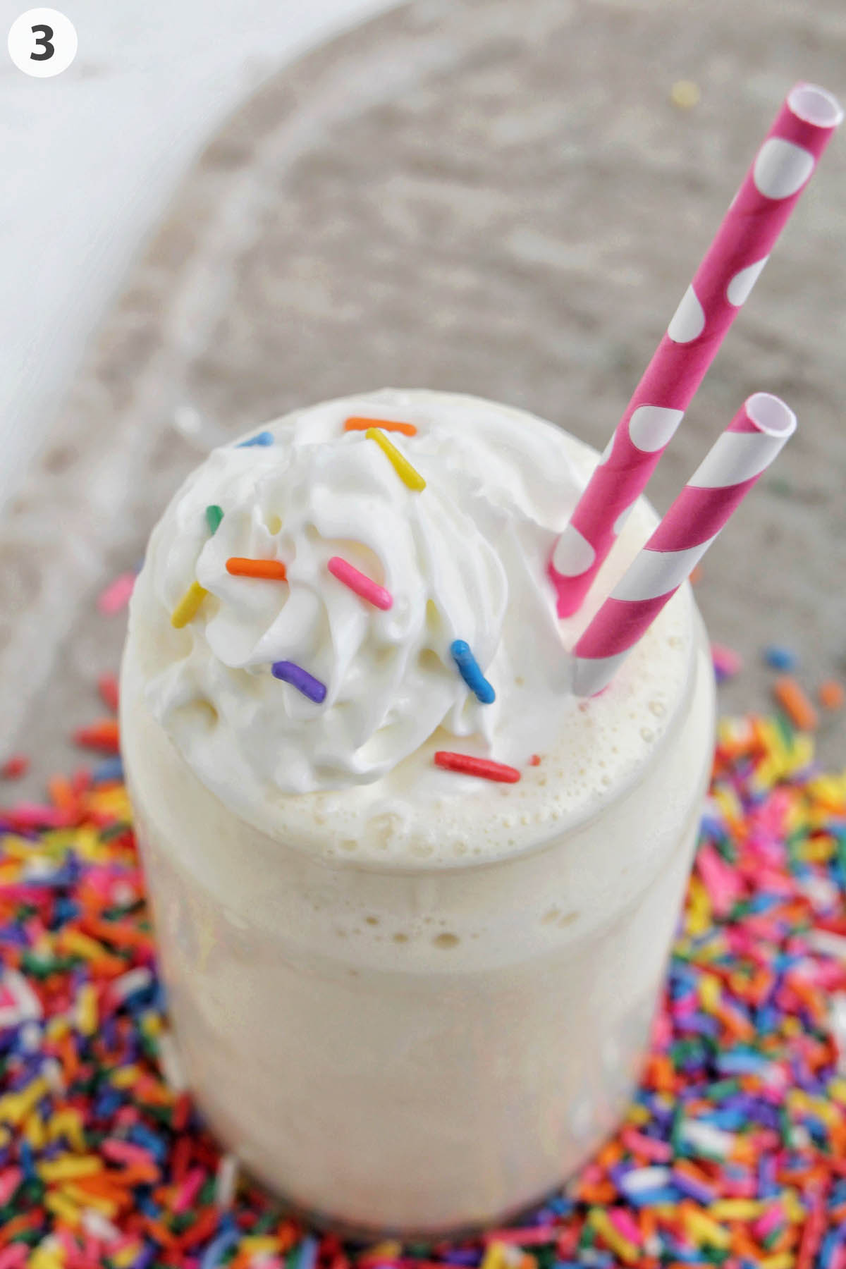 numbered photo of vanilla milkshake topped with whipped cream and sprinkles.