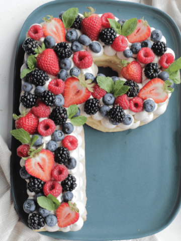 letter cookie cake with berries and mint leaves.