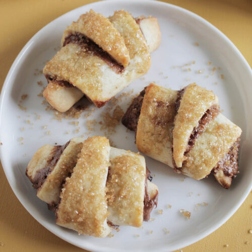 three chocolate rugelach cookies on a plate.