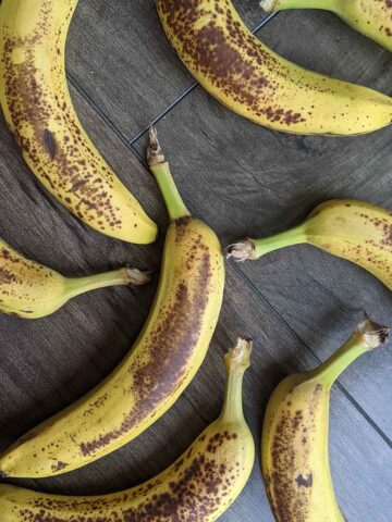 ripe bananas laying on a brown background.