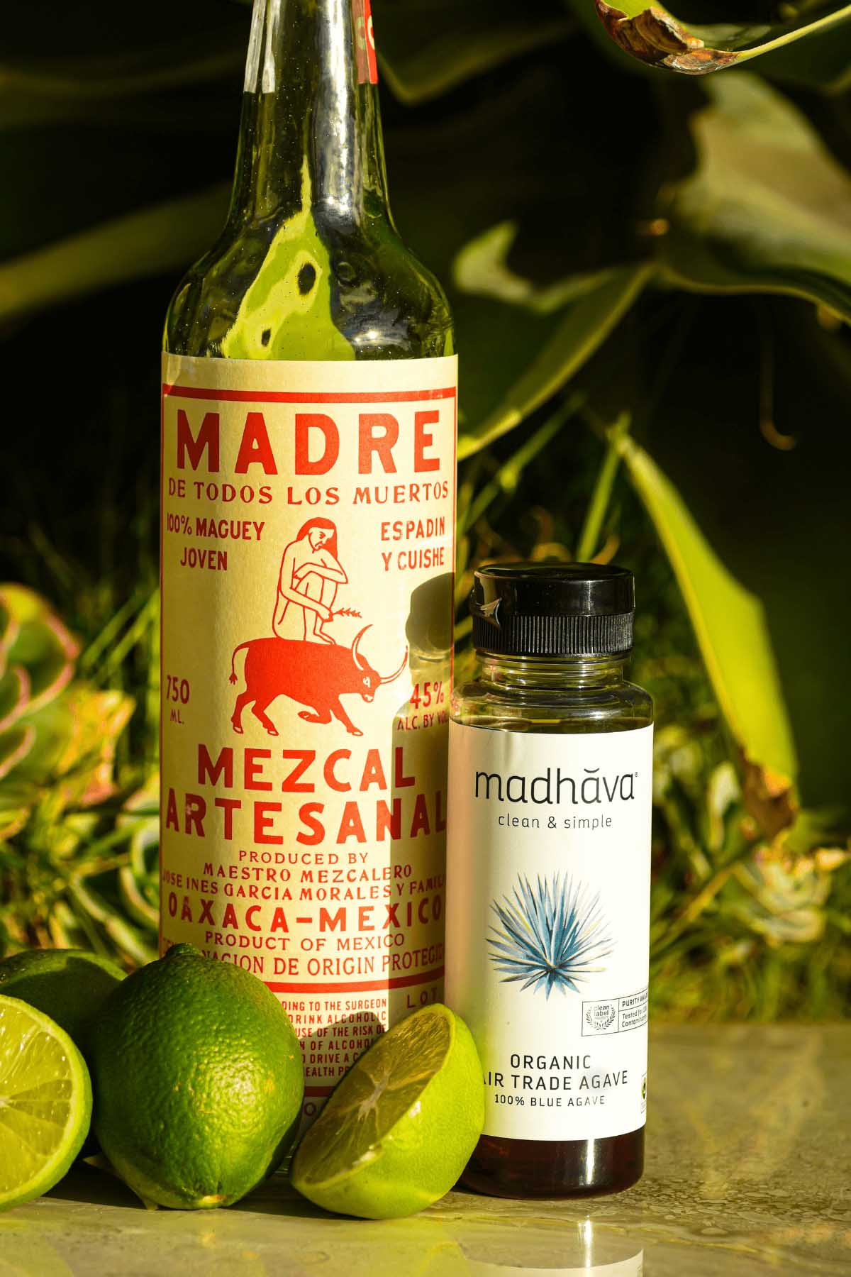 mezcal alcohol bottle next to agave syrup bottle.