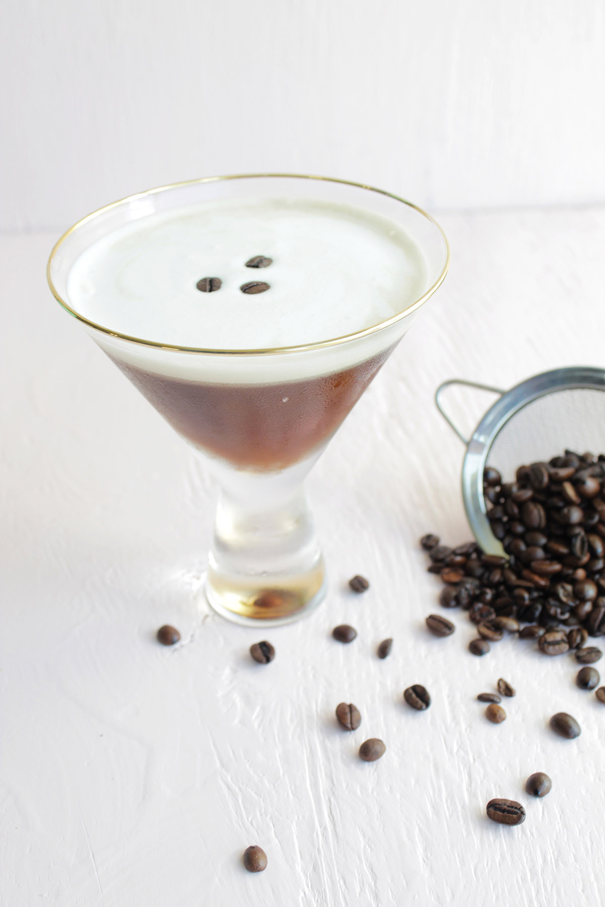 espresso martini cocktail next to a pile of coffee beans.