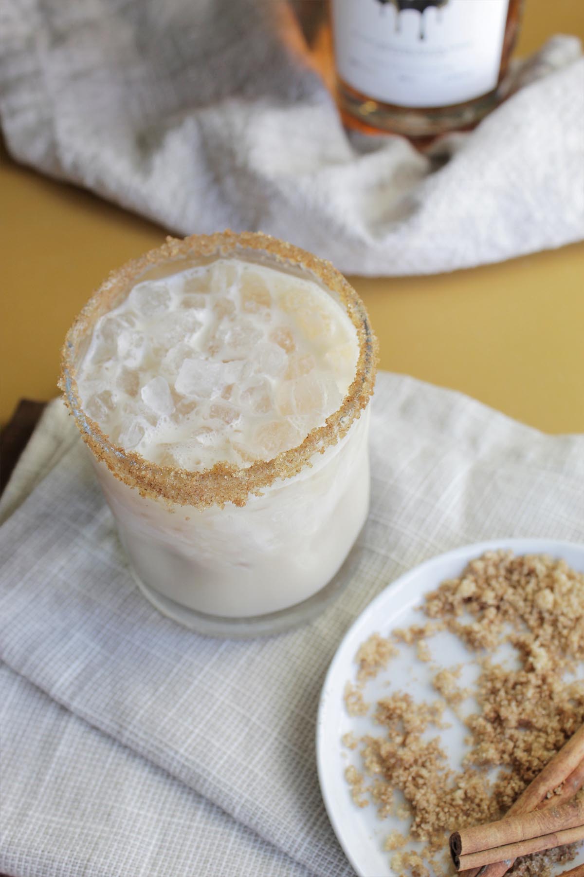 white cocktail with a brown sugar rim and pebble ice.