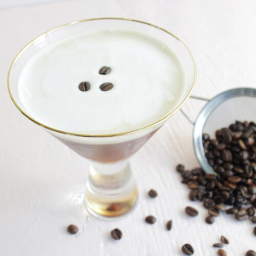 espresso martini topped with cold foam and garnished with three coffee beans.