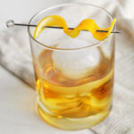 old fashioned in glass cup with orange twist.