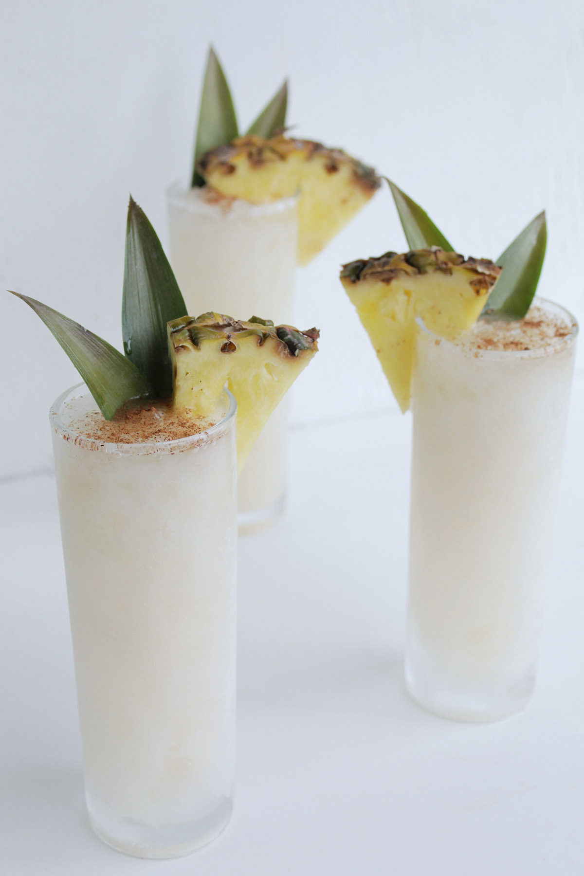 white tiki drinks with pineapple garnishes.