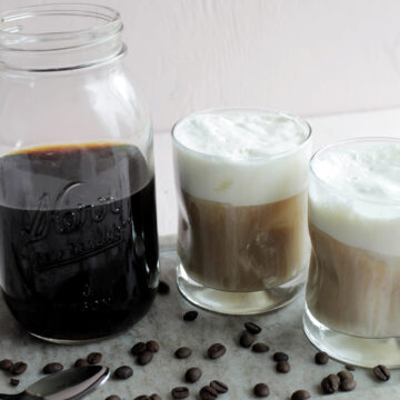 cold brew coffee next to two glasses of coffee with foam.