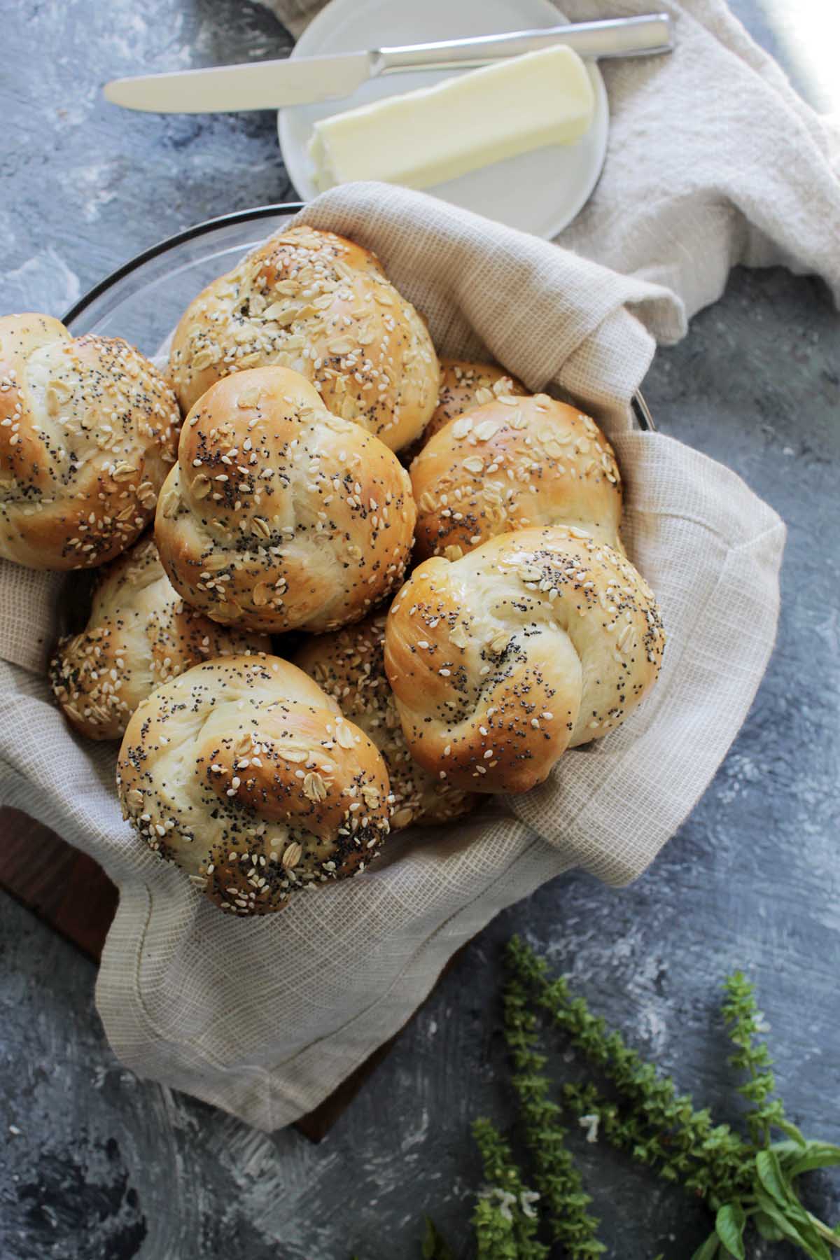 Bowl filled with knotted challah rolls.