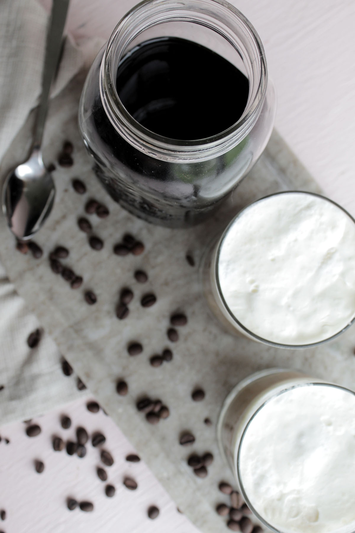 coffee in a mason jar next to two glasses of coffee with cold foam.