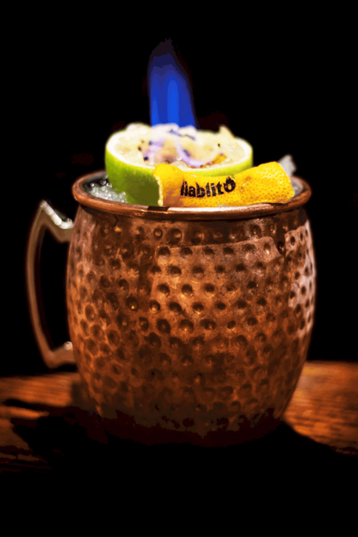 flaming lime on cocktail in copper mug
