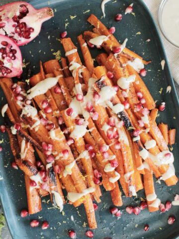 pan roasted carrots topped with pomegranate seeds.