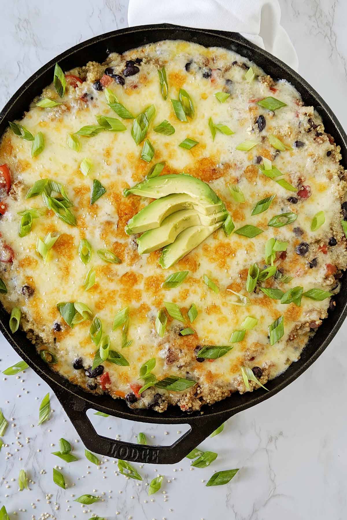 Cheesy Mexican casserole with green onion and avocado garnish
