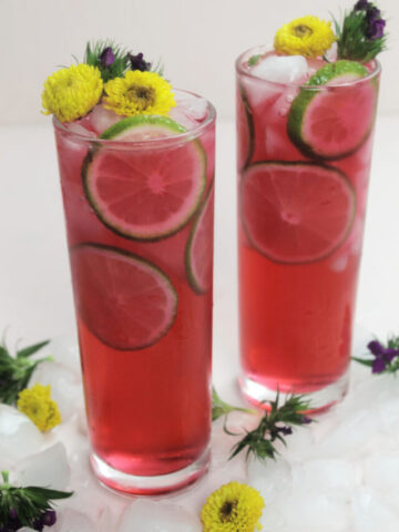hibiscus tea cocktail with sprite and tequila topped with flowers.