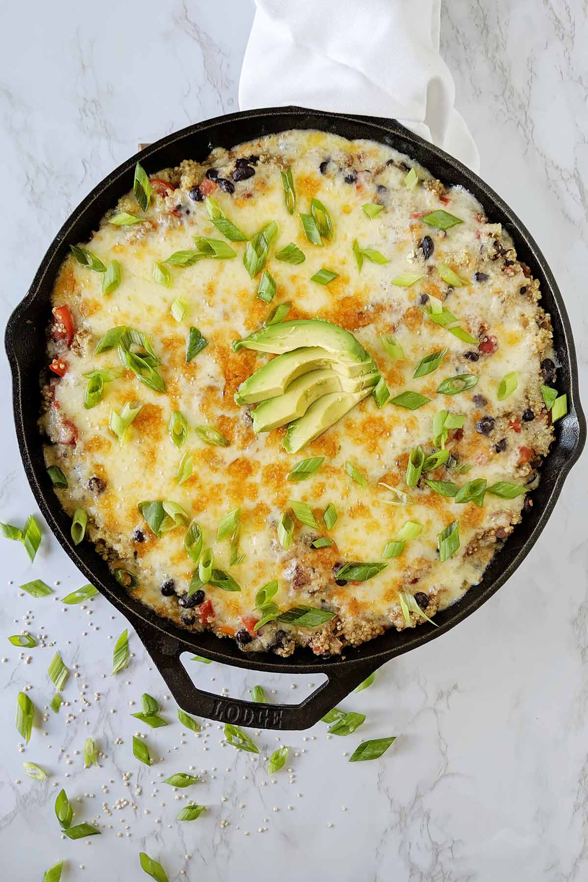 quinoa vegetarian casserole topped with cheese in cast iron skillet