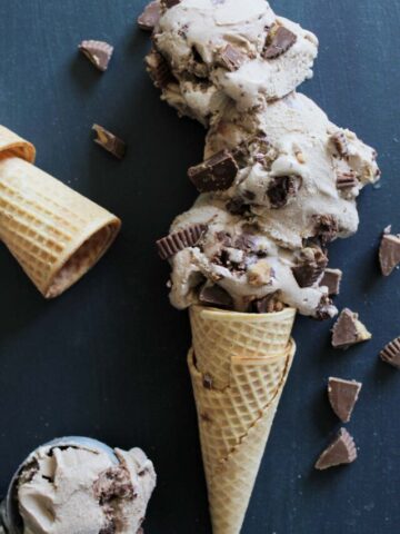 moose tracks ice cream scoops in a waffle cone on a navy blue background.
