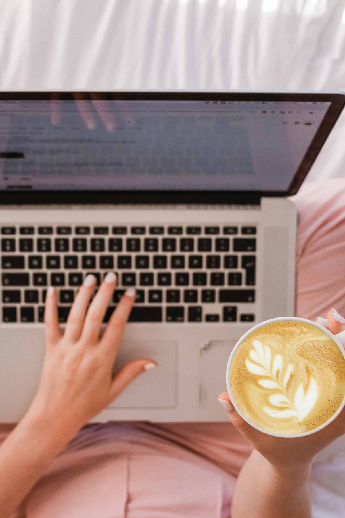 Macbook on girl's lap with coffee in hand