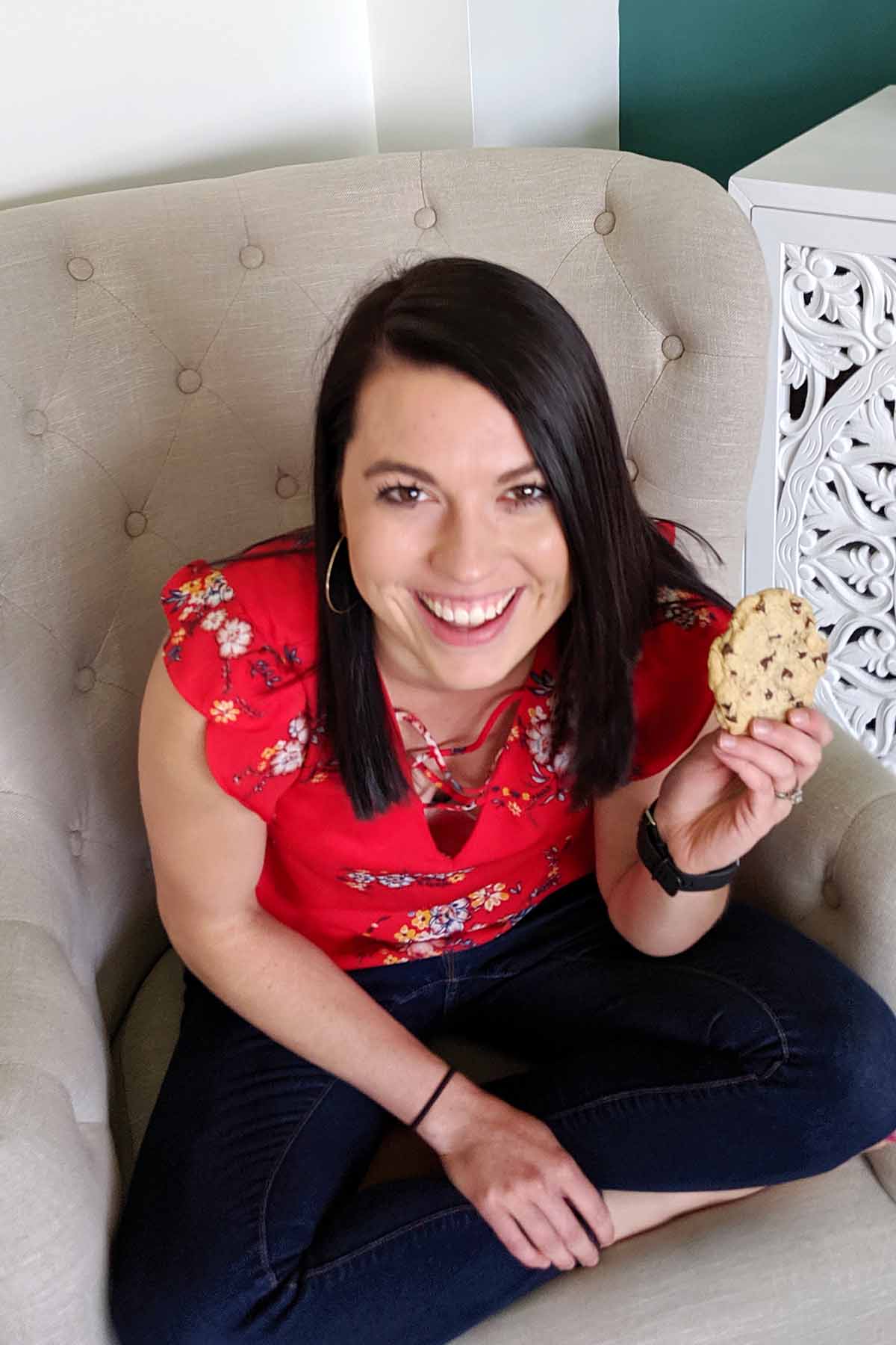 girl with brown hair and red shirt holding a cookie.