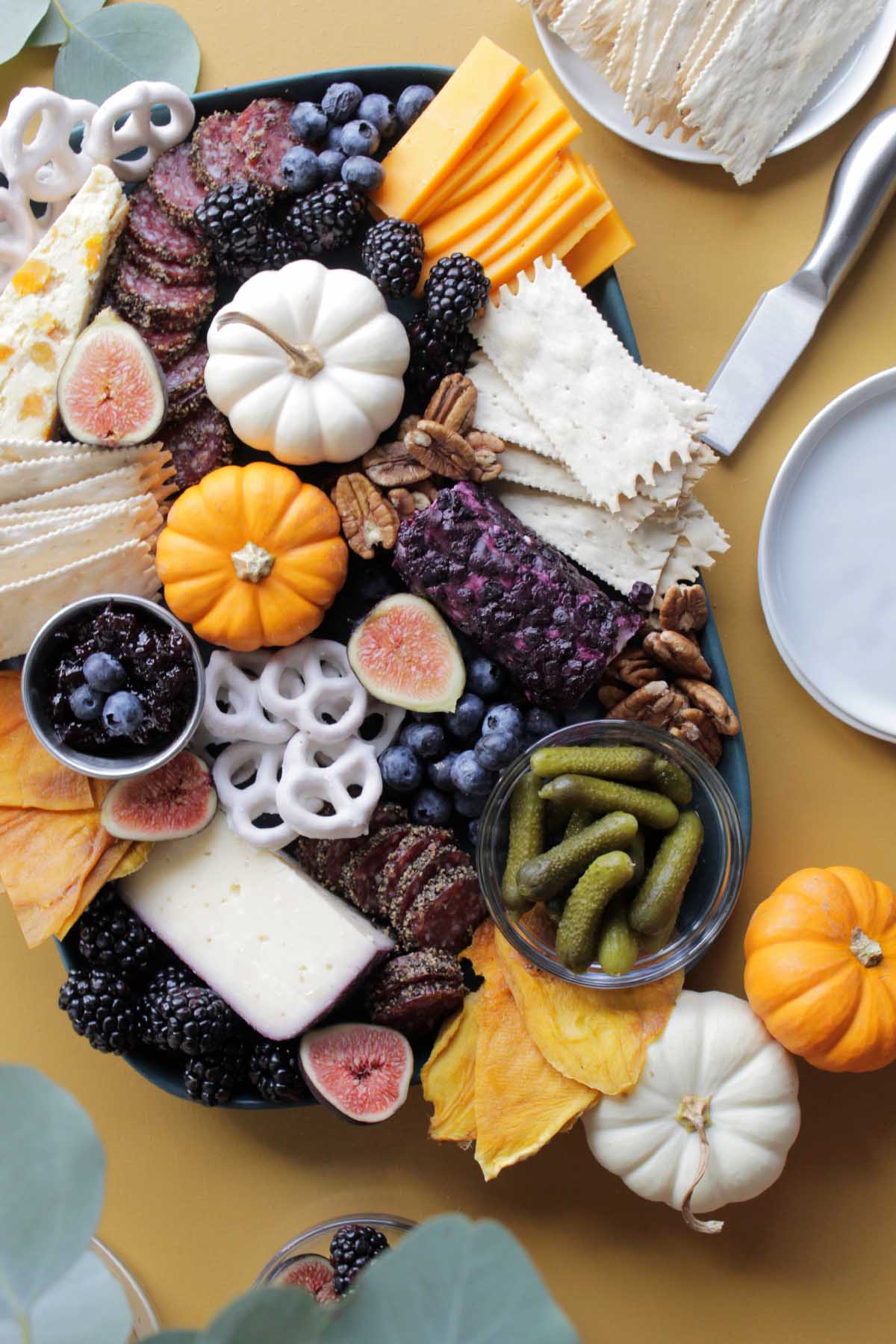 fall charcuterie board with orange, blue and white ingredients