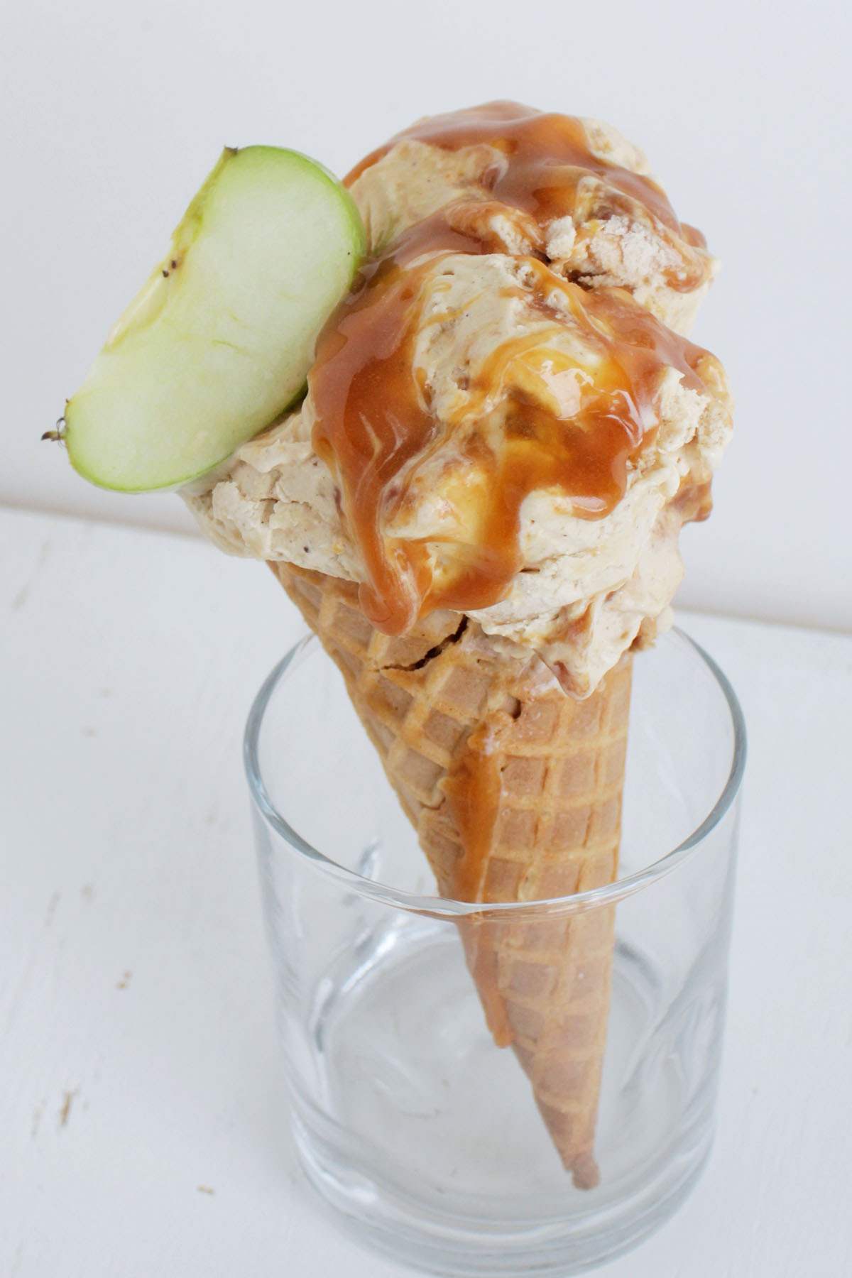 apple ice cream in waffles cone garnishes with apple wedge.