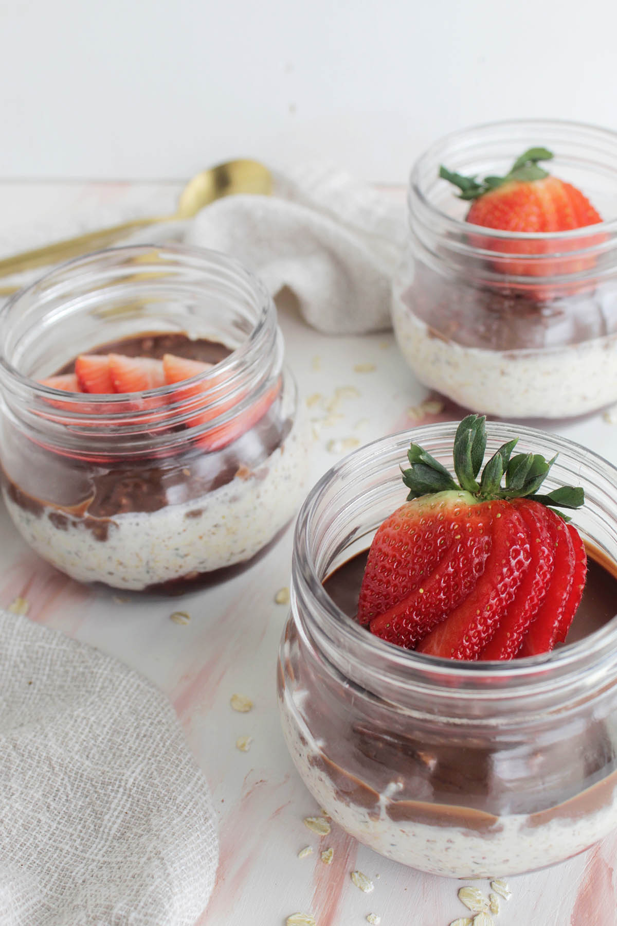 mason jars filled with overnight oats with strawberries on top.