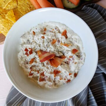 caramelized onion dip with bacon bits garnish on top.