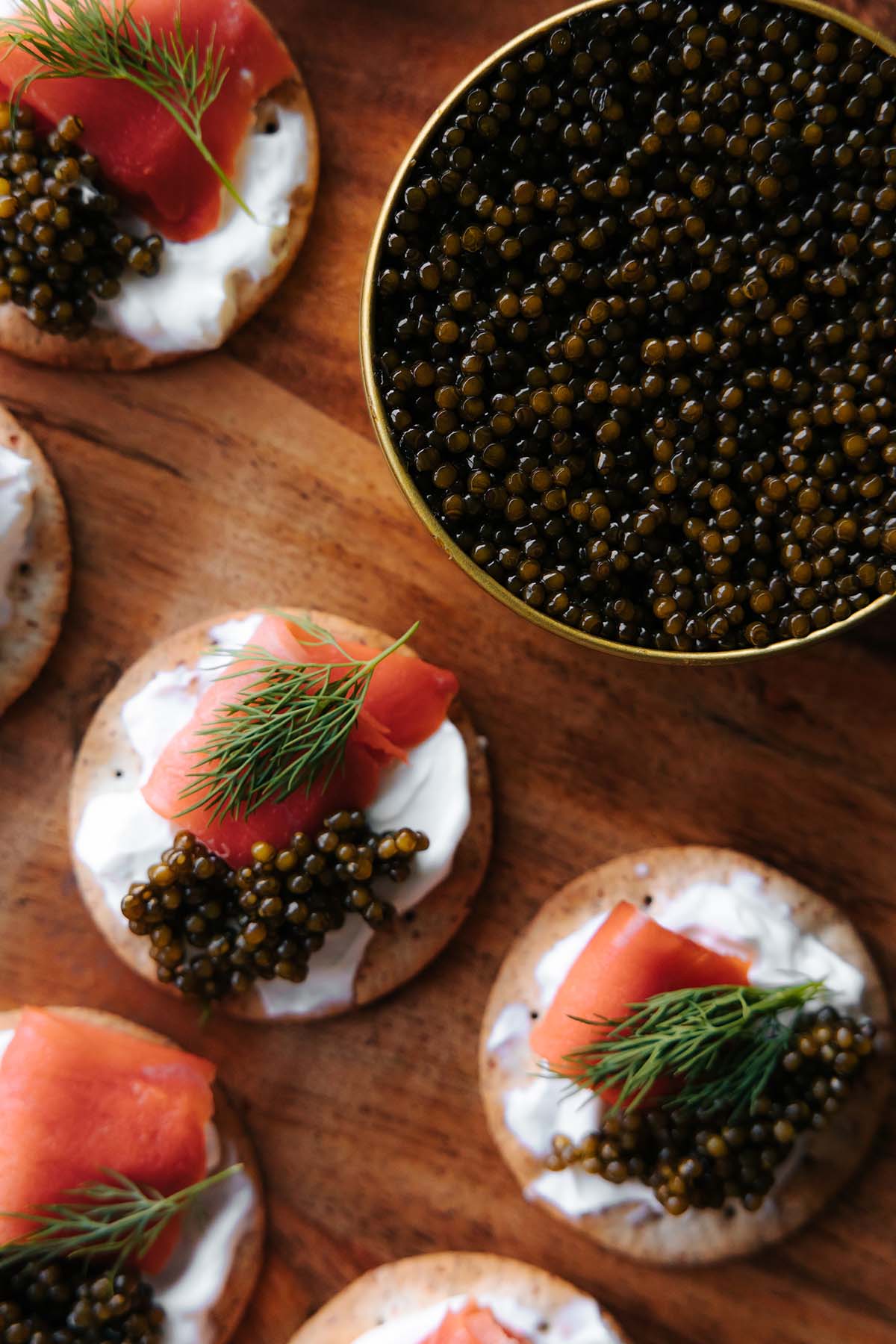 tin of caviar next to crackers with salmon.
