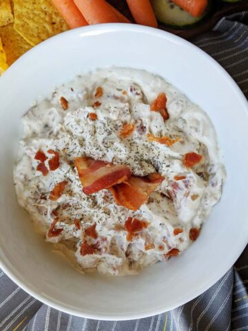 onion and bacon dip in a white bowl.